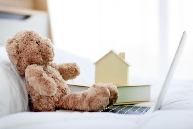 Joli ours en peluche pelucheux brun assis seul sur le lit dans la chambre.