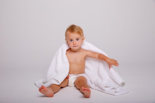 Joli petit bébé avec une serviette douce sur fond blanc
