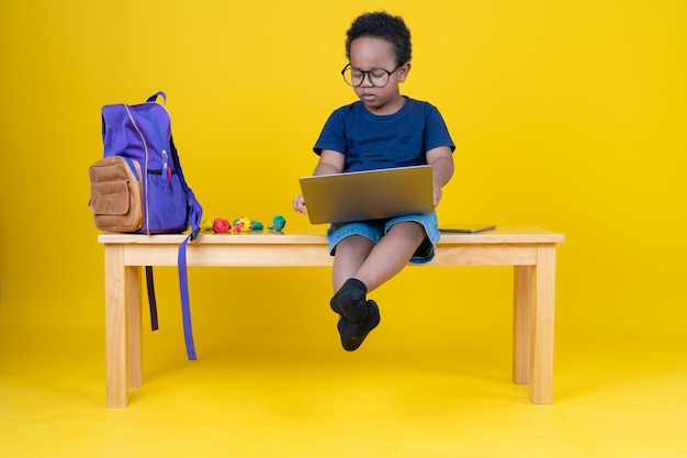 Joli petit garçon apprenant Internet ou jouant à des jeux avec son ordinateur portable