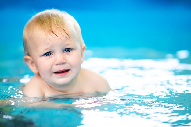 Joli petit garçon apprenant à nager dans une piscine spéciale pour les petits enfants