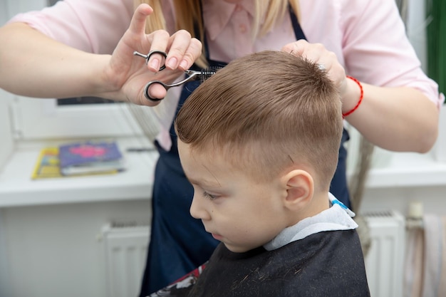 Joli petit garçon européen se coiffant dans un salon de coiffure