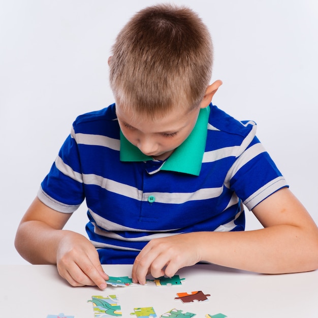 Joli petit garçon jouant aux puzzles à la table