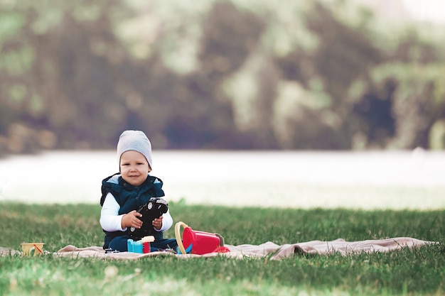 Joli petit garçon jouant avec des jouets assis sur la pelouse dans le parc