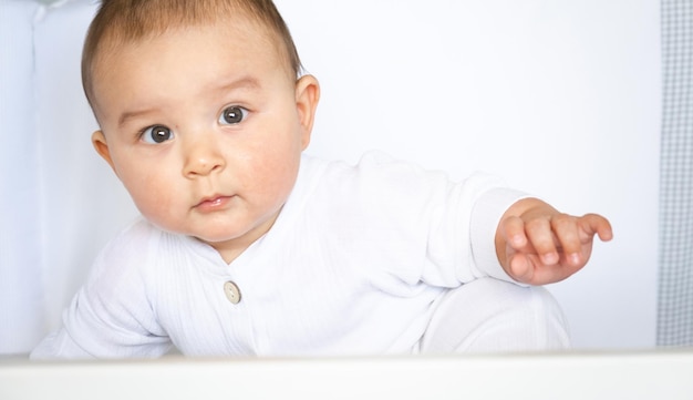 Joli portrait d'un bébé dans un berceau en gros plan Un enfant en vêtements blancs sur des sous-vêtements blancs Tendresse et soin des problèmes des enfants