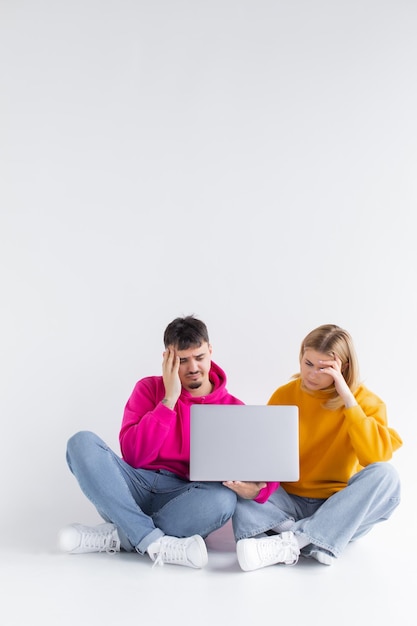 Joli portrait de couple avec ordinateur portable assis fond gris