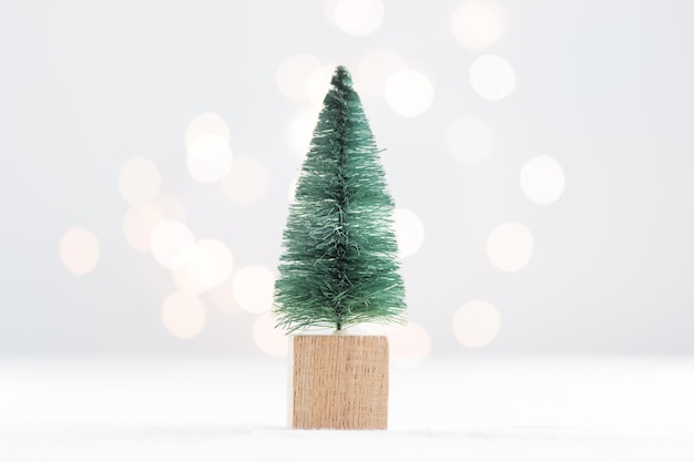 Joli sapin miniature de Noël sur un tableau blanc avec des lumières bokeh