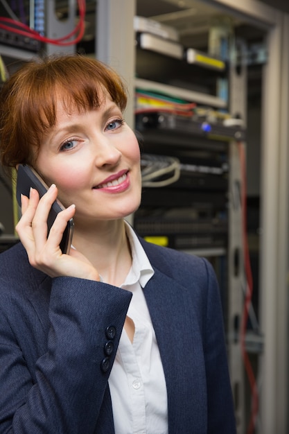 Joli technicien en informatique parlant au téléphone à côté du serveur ouvert