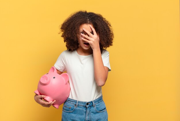 Jolie adolescente afro à l'air arrogante, réussie, positive et fière, se montrant elle-même. concept d'épargne