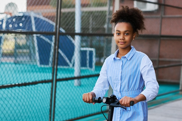 Jolie adolescente afro-américaine avec scooter électrique