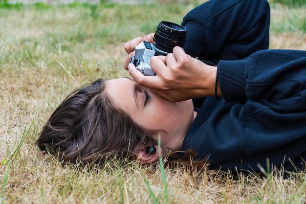 Jolie adolescente avec un appareil photo une fille prenant des photos sur un appareil photo vintage rétro sur l'herbe