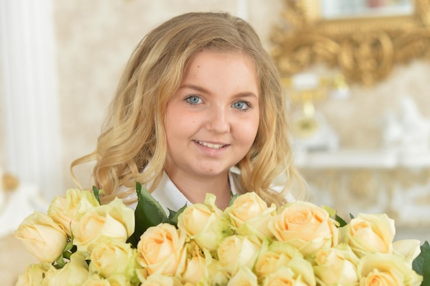 Jolie adolescente bouclée posant avec bouquet de roses jaunes