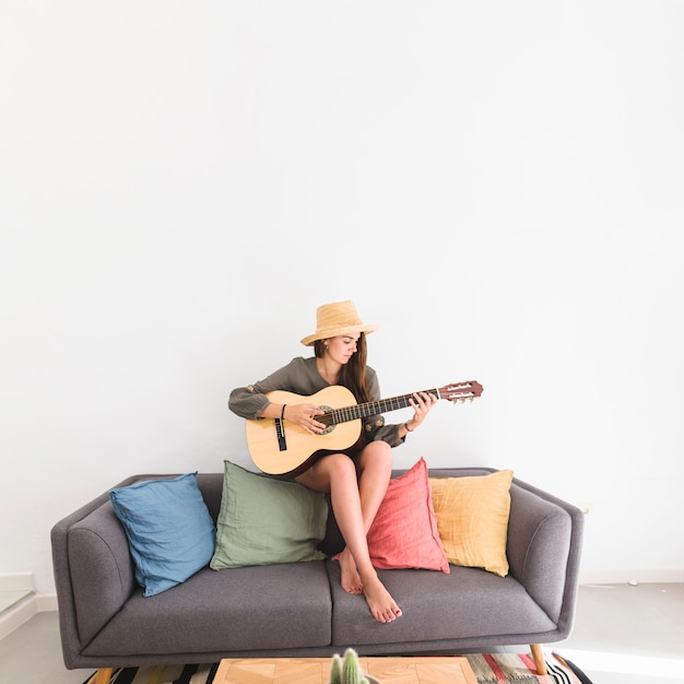 Photo jolie adolescente, chapeau, jouer, guitare, chez soi