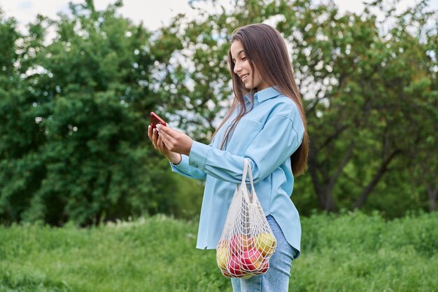 Jolie adolescente dans le parc à l'aide de smartphone