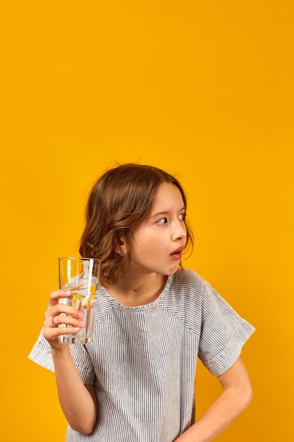 Jolie adolescente enfant avec un verre d'eau fraîche isolé
