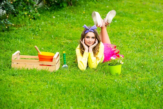 Jolie adolescente heureuse avec des fleurs dans un pot jardin