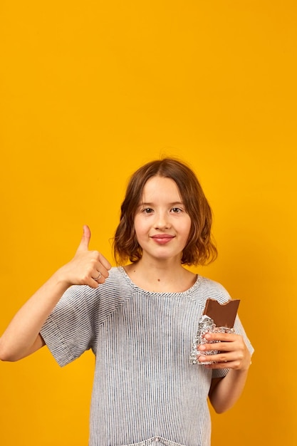 Jolie adolescente mange des bouchées une barre de chocolat