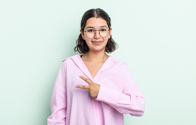 Jolie adolescente se sentant heureuse, positive et réussie, avec la main en forme de v sur la poitrine, montrant la victoire ou la paix