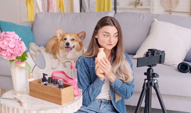 Jolie adolescente avec son chien mignon Vlogging tout en faisant un maquillage. Jeune fille en train de filmer son vidéoblog de beauté. Une jeune fille dirige un enseignement à distance sur le maquillage pendant les blogs.