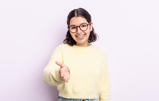 Jolie adolescente souriante, l'air heureuse, confiante et amicale, offrant une poignée de main pour conclure un accord, coopérant