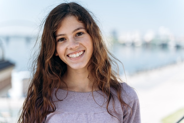 Jolie adolescente souriante, regardant la caméra, vue rapprochée. Une jeune fille souriante pose sur le site de la ville