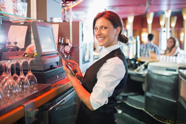 Jolie barmaid utilisant l&#39;écran tactile jusqu&#39;à