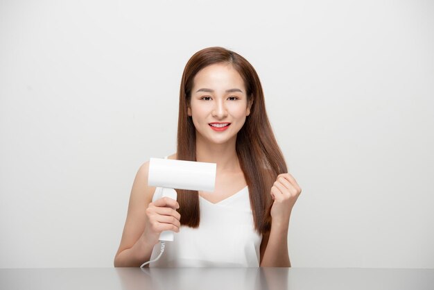 Jolie belle femme asiatique soufflant le vent par sèche-cheveux