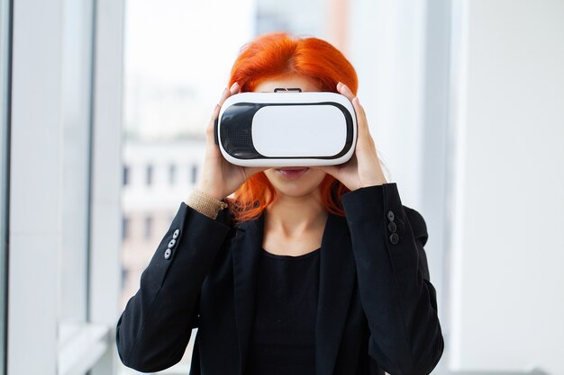 Jolie belle femme excitée mignonne dans un casque VR essayant de toucher des objets en réalité virtuelle
