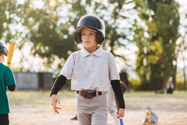 Jolie et belle fille dans un casque marche sur un terrain de baseball