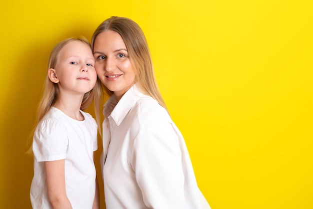 Jolie belle mère et fille en vêtements blancs Embrassez la famille Lieu de fond jaune pour le texte Photo de haute qualité