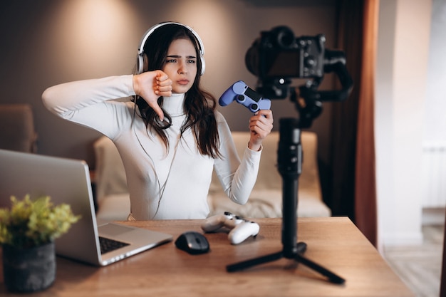 Une jolie blogueuse au casque diffuse en direct des discussions sur les jeux vidéo. Influenceuse jeune femme en direct en streaming. Ne pas aimer.