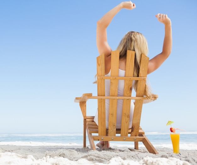 Jolie blonde assise sur une chaise longue avec un cocktail