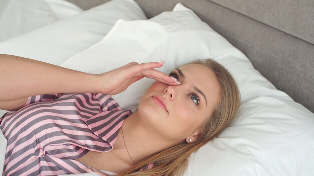 Jolie blonde aux yeux bleus se réveille au lit le matin