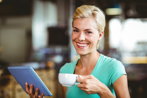 Jolie blonde ayant un café à l&#39;aide de tablet pc