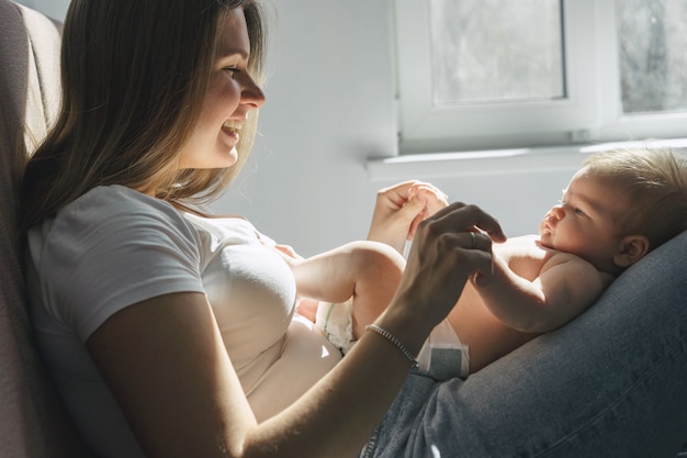 Photo une jolie blonde entend depuis longtemps maman et son fils nouveau-né sur ses jambes dans la chambre blanche des enfants