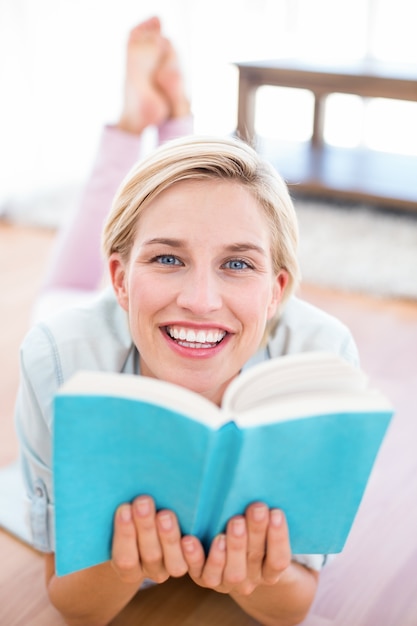 Jolie blonde femme allongée sur le sol et lire un livre