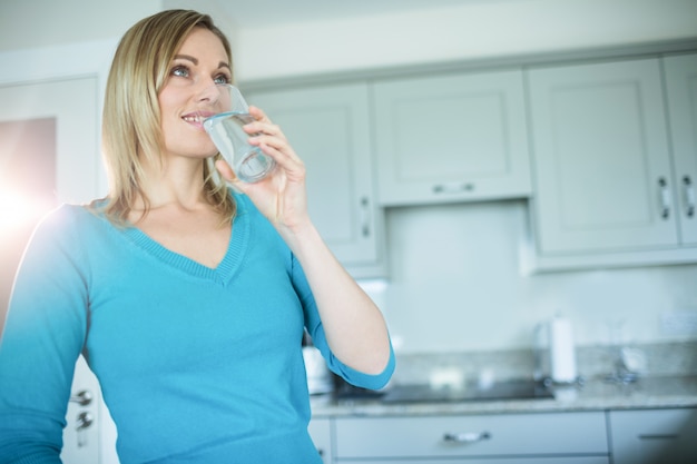 Jolie blonde femme buvant un verre d'eau