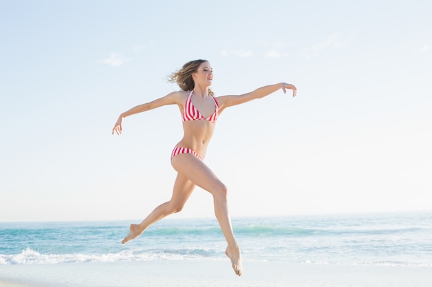 Jolie blonde femme sautant sur la plage