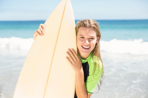 Jolie blonde femme tenant une planche de surf