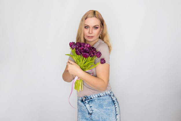 Jolie blonde femme tenant des tulipes violettes dans ses mains