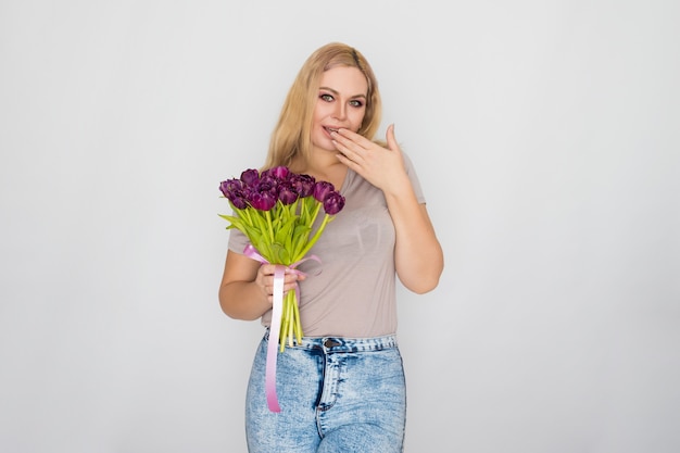 Jolie blonde femme tenant des tulipes violettes dans ses mains