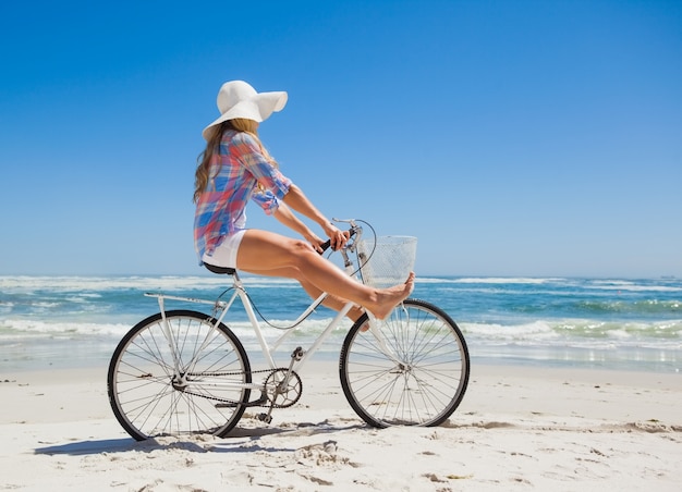 Jolie blonde insouciante sur une balade à vélo à la plage