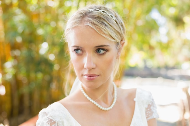 Jolie blonde mariée debout sur un pont en détournant les yeux