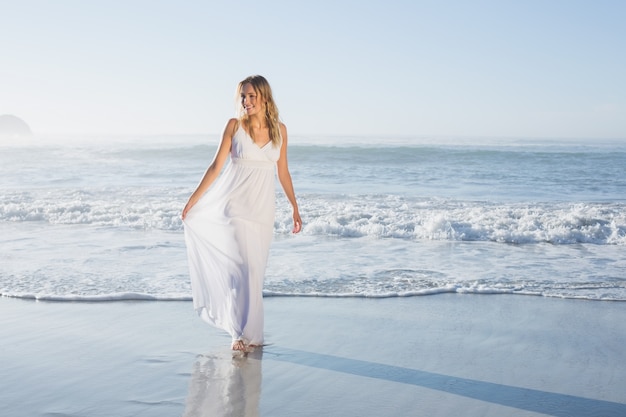 Jolie blonde à la plage en robe blanche