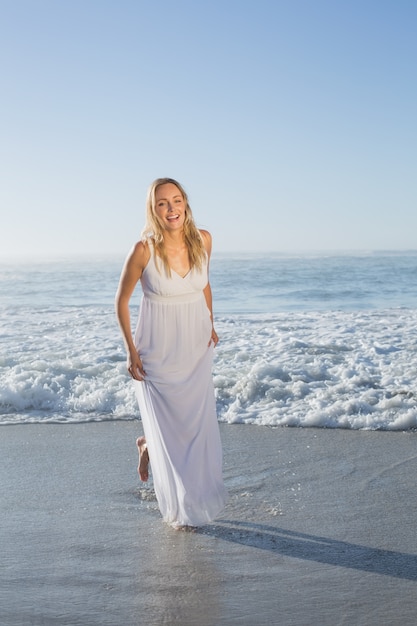 Jolie blonde à la plage en robe blanche