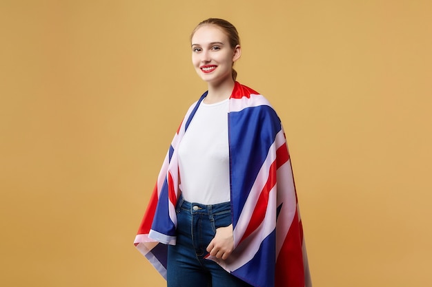 Jolie blonde pose avec un drapeau britannique. séance photo en studio sur fond jaune.