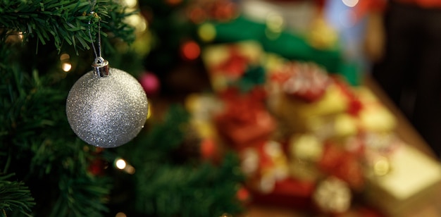 Une jolie boule argentée vive accrochée à un arbre de Noël traditionnel comme une belle décoration d'ornement pour une merveilleuse fête à la maison du nouvel an la nuit d'hiver. Ajoutez du bruit pour s'adapter à l'image de style vintage
