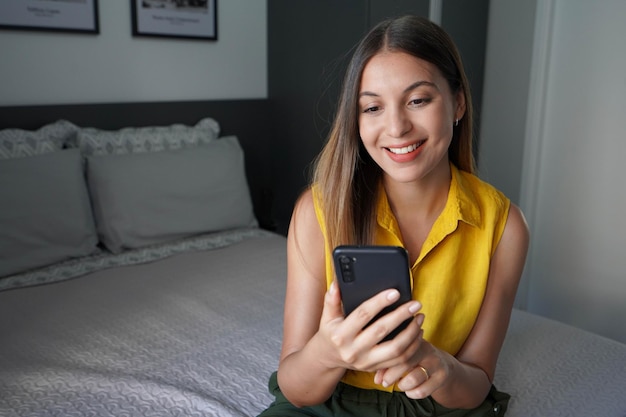 Photo une jolie brésilienne qui utilise un téléphone portable dans sa chambre à la maison.