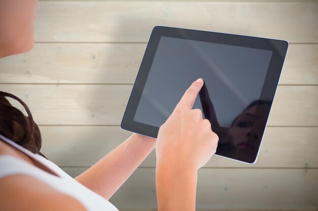 Jolie brune à l'aide de tablet pc sur fond de planches de bois blanchi