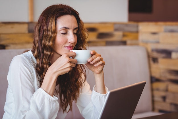 Jolie brune ayant du café en utilisant un ordinateur portable