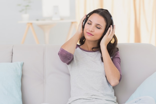 Jolie brune écoute de la musique sur le canapé